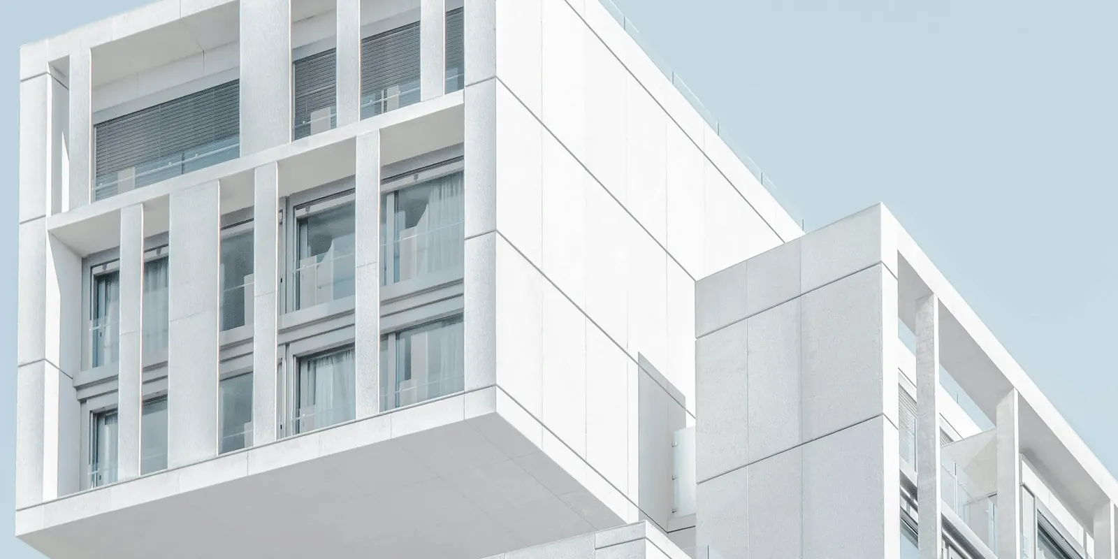 Clean white modern concrete building against a calm blue sky